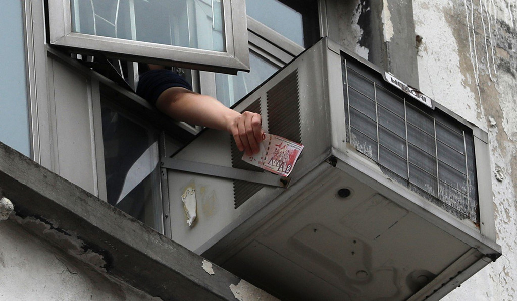 Một người dân nhặt tờ tiền 100 HKD rơi xuống trong cơn mưa tiền hôm 15/12. Ảnh: Sam Tsang